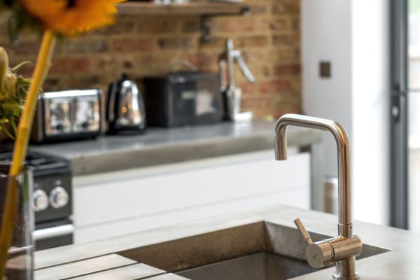 concrete kitchen island with brushed metal tap and sink
