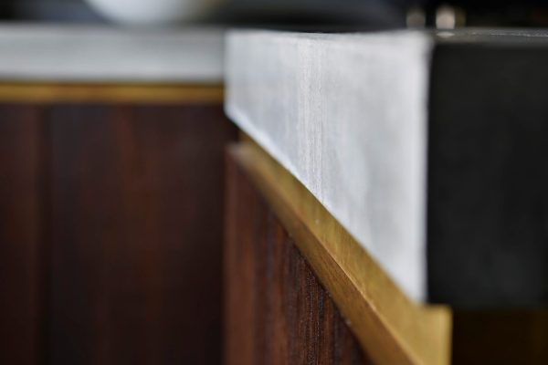 Close-up of thick polished concrete worktop edge with brass detailing