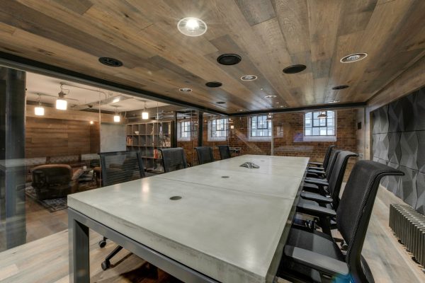 Large concrete conference table beneath timber ceiling in London office